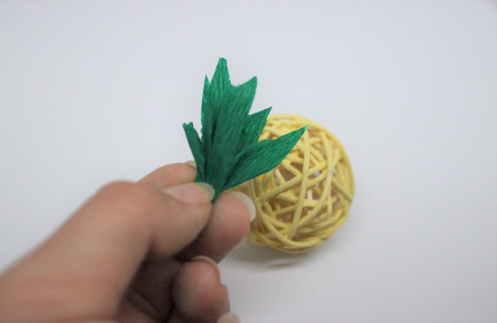 DIY Deko Ananas Krepppapier wird an der Dekokugel angebracht