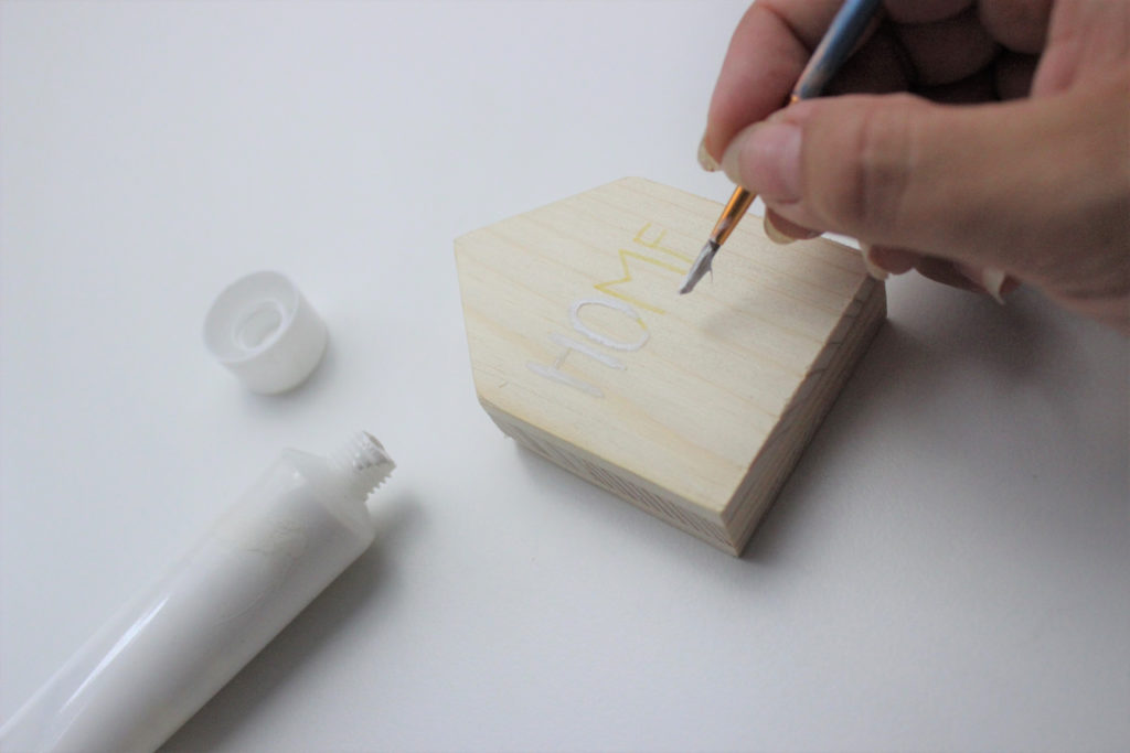 Fotohalter aus Holz in Hausform wird bemalt. 