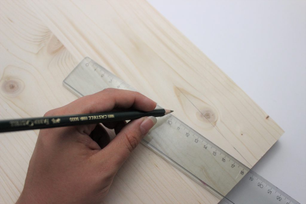 Das Maß des Fotohalters wird auf eine Holzplatte mit einem Bleistift und einem Lineal übertragen. 