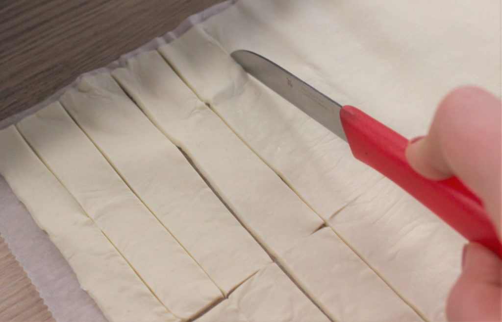 Der Blätterteig wird in Streifen geschnitten für den selbst gemachten Partysnack. 