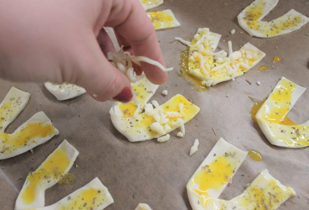 Der Partysnack wird mit Käse und Pizzagewürz verfeinert. 