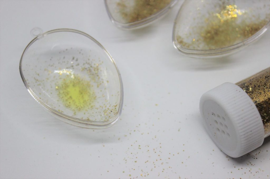 Die halben Ostereier werden mit Öl und Glitzer befüllt. 