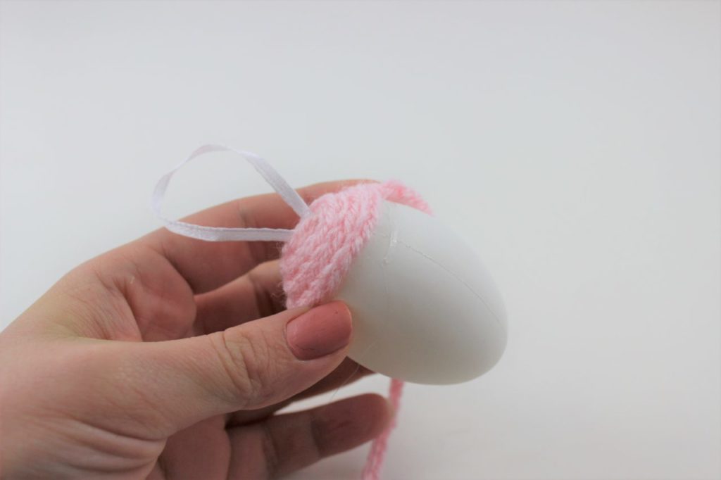 Die Häkel Schlange wird um das Plastikei geklebt. 