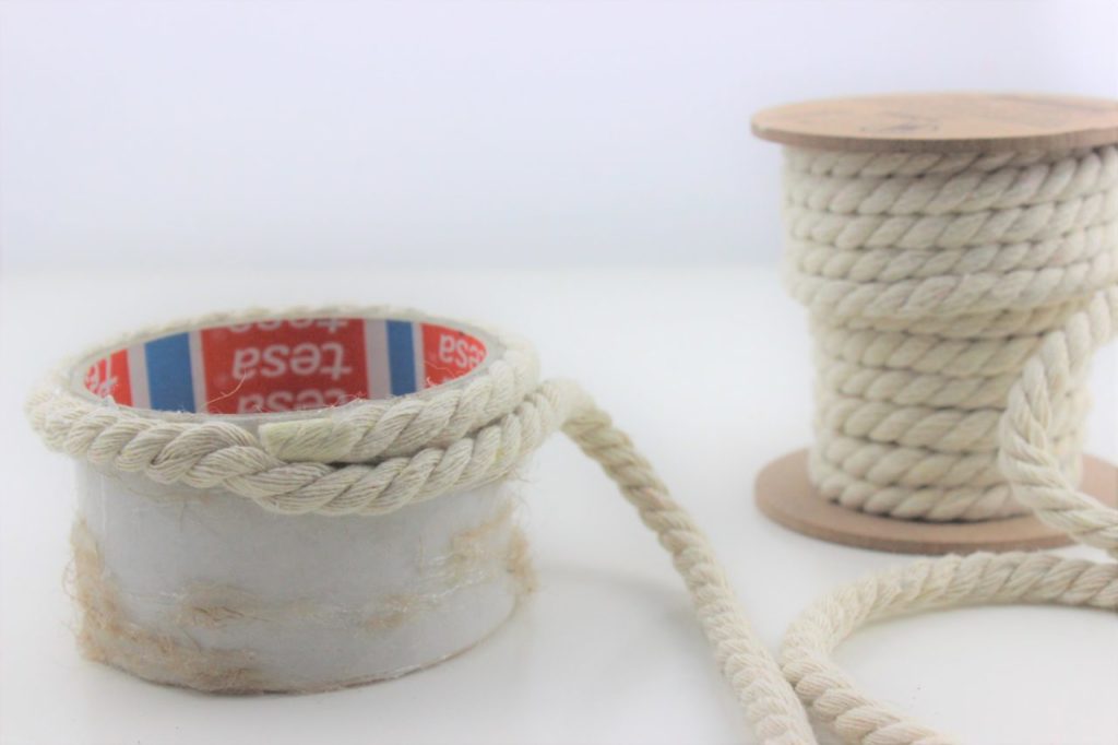 Die Kordel wird um die leere Klebebandrolle geklebt und ein DIY Kerzenhalter entsteht.