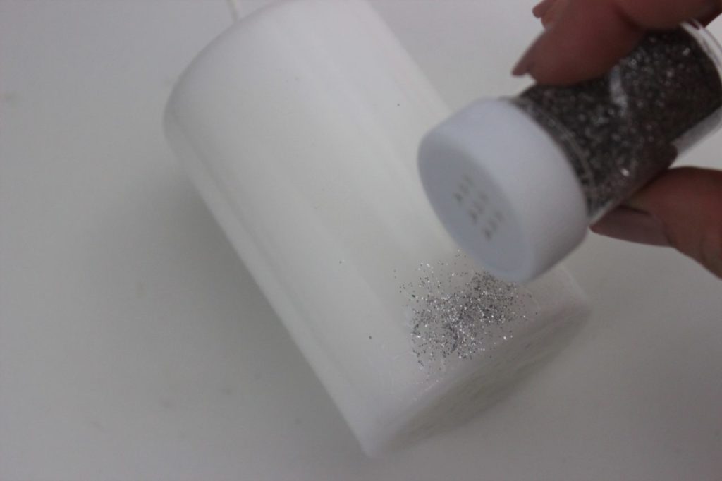 Die Kerze wird mit Kleber bestrichen und mit ein wenig Glitzer dekoriert.