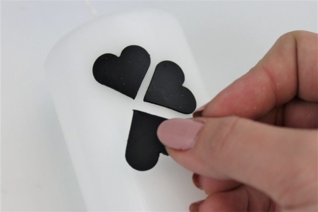 Die Herzen werden in Form eines Kleeblattes auf die Kerze gedrückt.