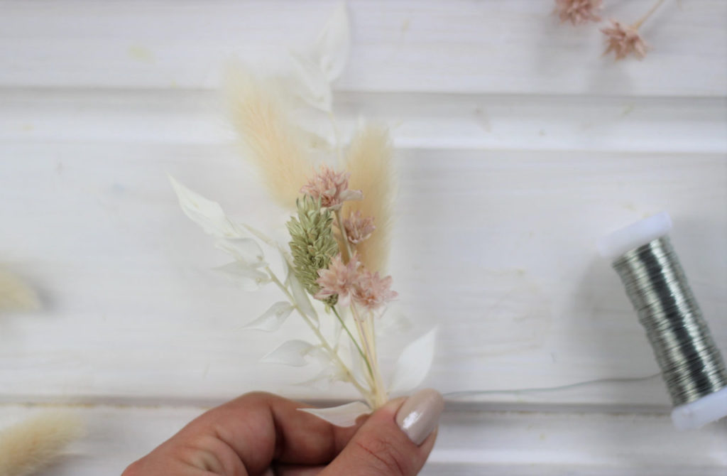Die Trockenblumen werden zu kleinen Sträußen gebunden bevor sie am Dekoring befestigt werden.