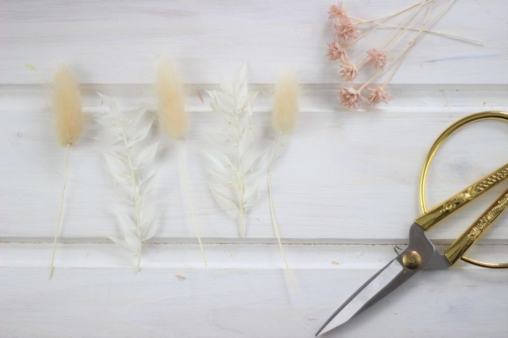 Die Trockenblumen werden für den DIY Kranz auf die richtige Länge zugeschnitten.