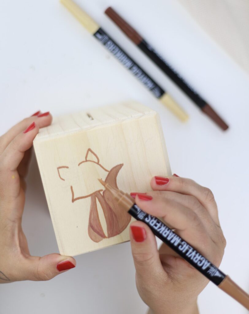 Mit speziellen Stiften wird der Fuchs auf der Holzspardose ausgemalt