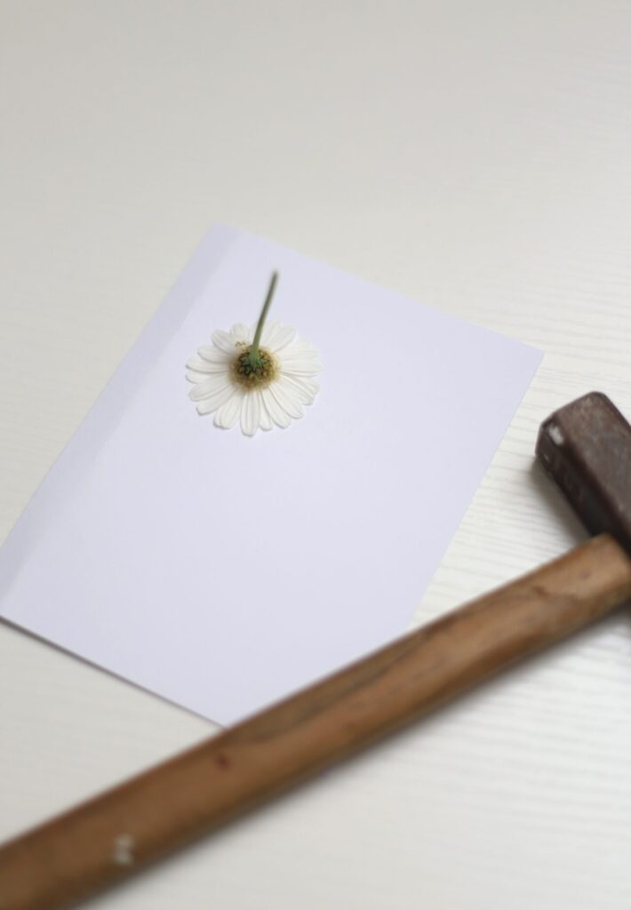 Die Blume wird mit Hilfe eines Hammers gedruckt